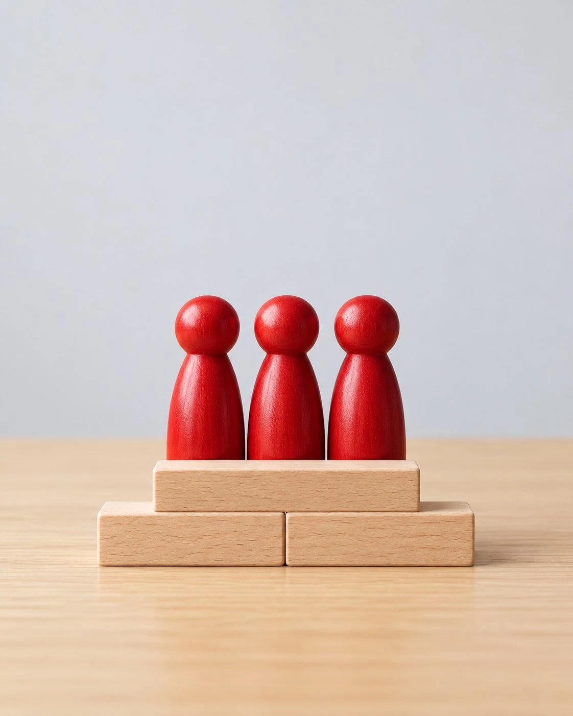 Three red figures standing side by side on wooden blocks
