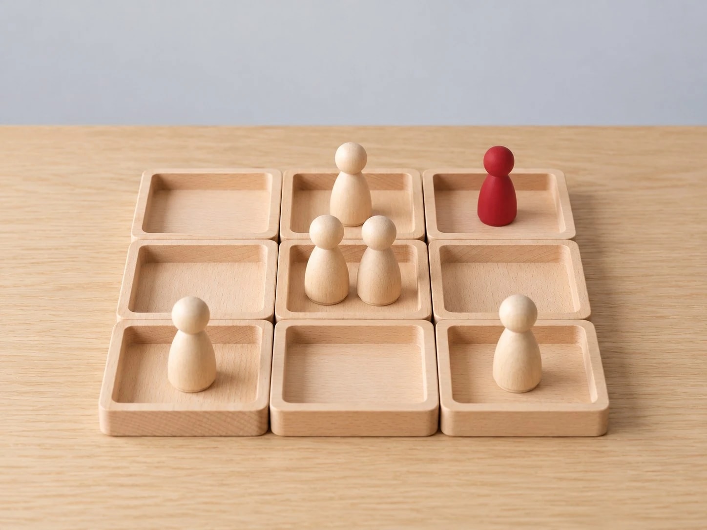 Wooden figures placed in a nine-box grid, one of them red