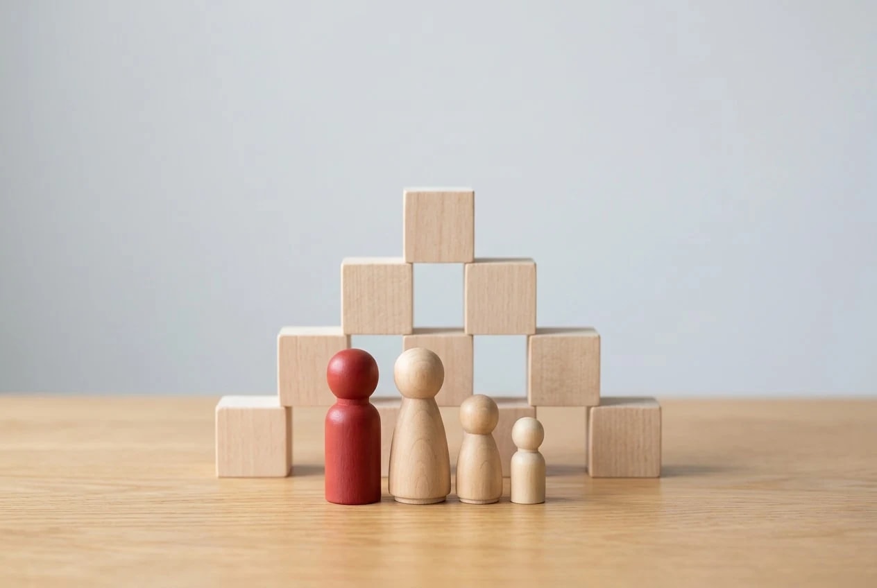 A family of wooden figures of different sizes standing in front of a pyramid of wooden cubes